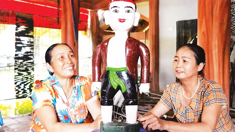 Nghệ nhân Ưu tú Nguyễn Thị Thỏa (bên trái) giới thiệu về rối nước Ðào Thục.